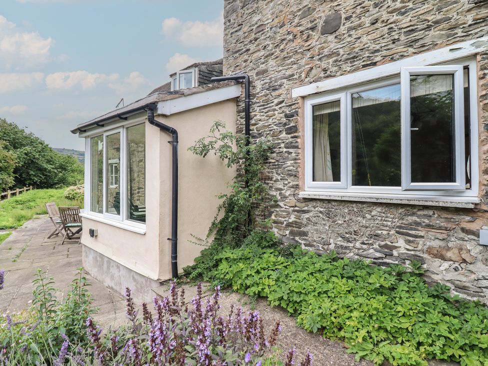 An outdoor view of a stone wall with windows and patio furniture at Hafod Llangollen