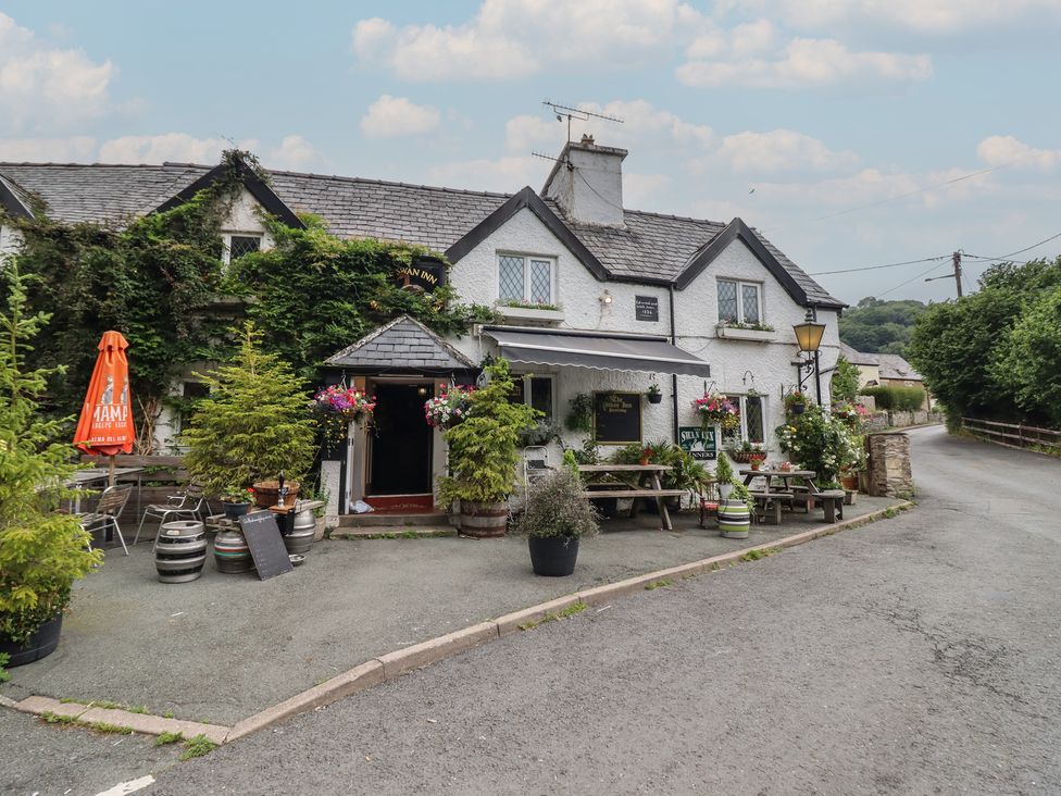 A pub entrance with benches and flower pots at The Swan Inn in Llangollen