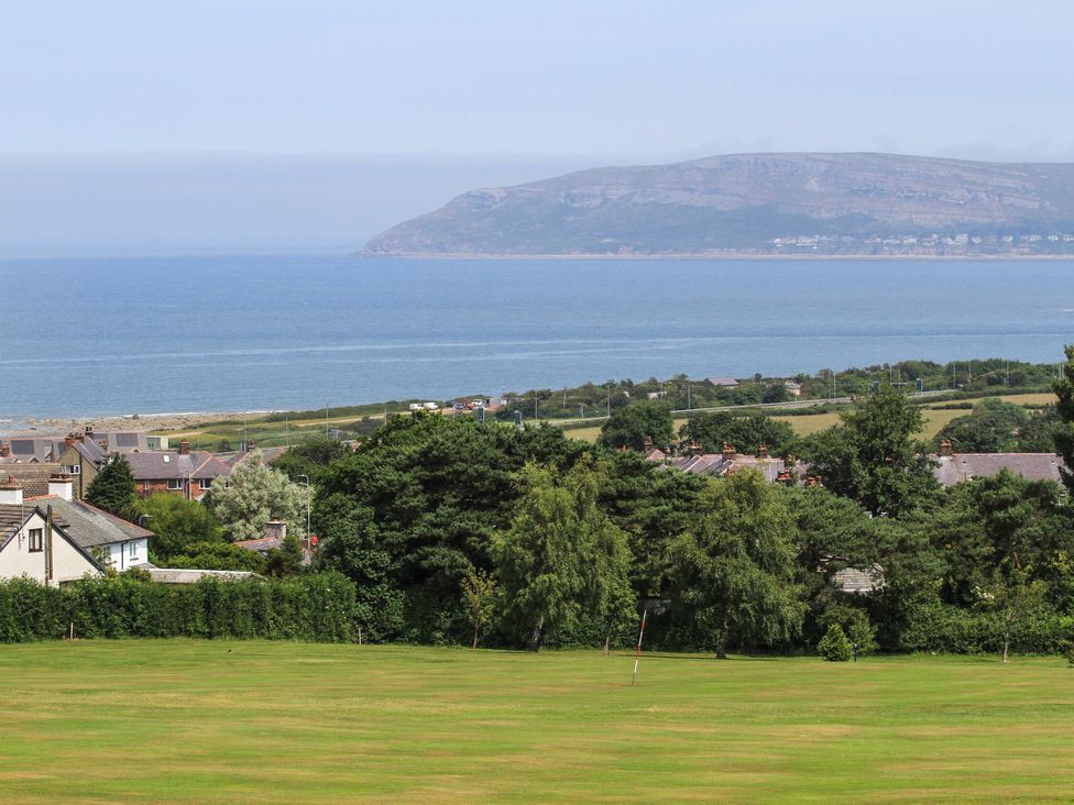 A view of the sea and hills from a grassy area at Bryn Hyfryd in Conwy
