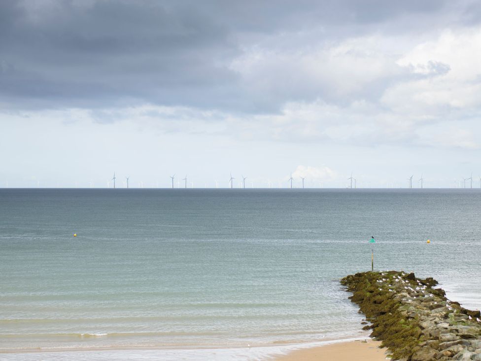 A seascape with wind turbines in the distance and a jetty in the foreground at Bryn Hyfryd in Conwy