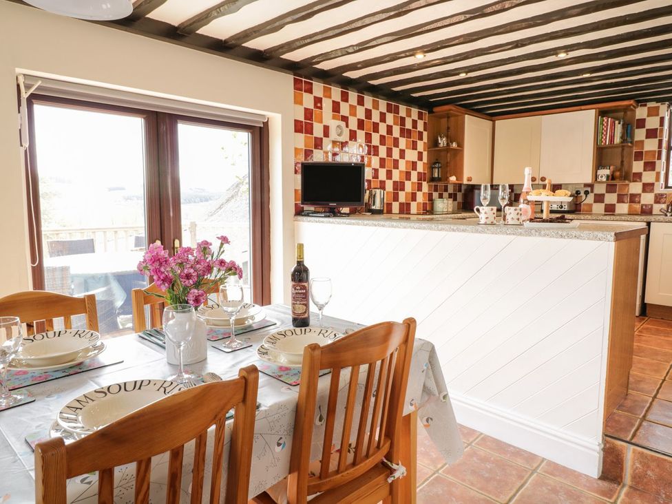 A kitchen with a dining table and chairs at Cyffdy Cottage - Aran Bala
