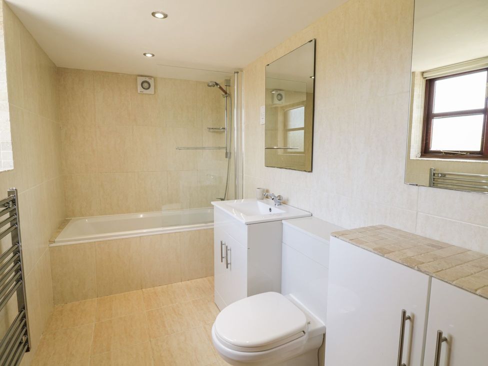 A bathroom with a bath tub, toilet, and sink at Cyffdy Cottage - Aran Bala