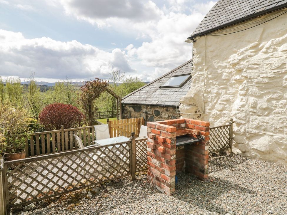 An outdoor area with a grill, seating, and a fenced patio at Cyffdy Cottage - Tegid in Bala