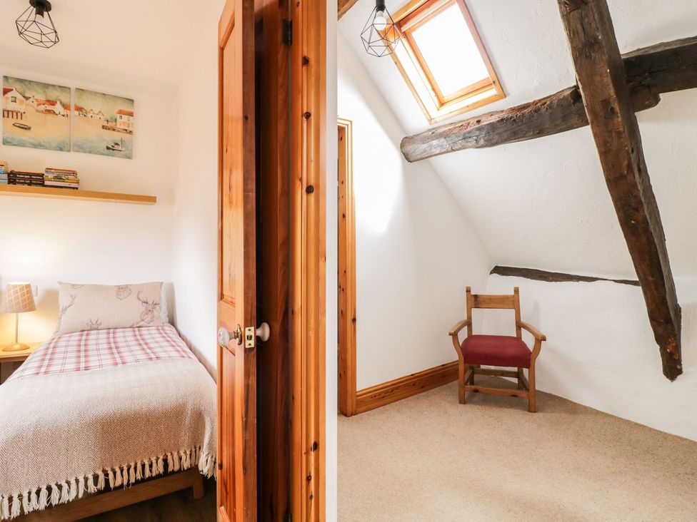 A bedroom with a bed and a chair at Cyffdy Cottage - Tegid Bala