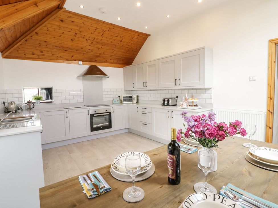 A kitchen with cabinets and a dining table at Cyffdy Cottage - Tegid in Bala
