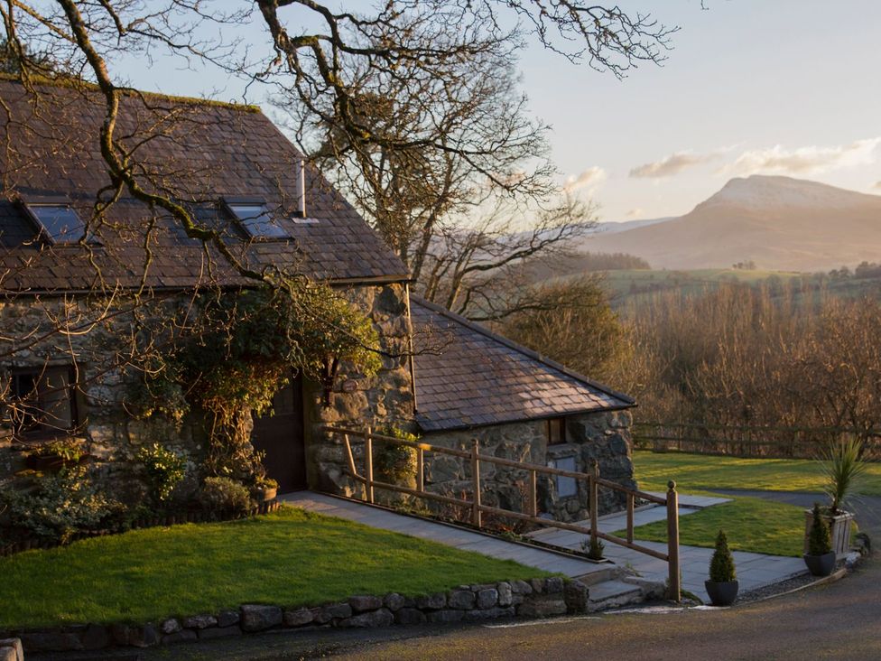 A cottage with a pathway leading to it and mountains in the background at Cyffdy Cottage - Tegid