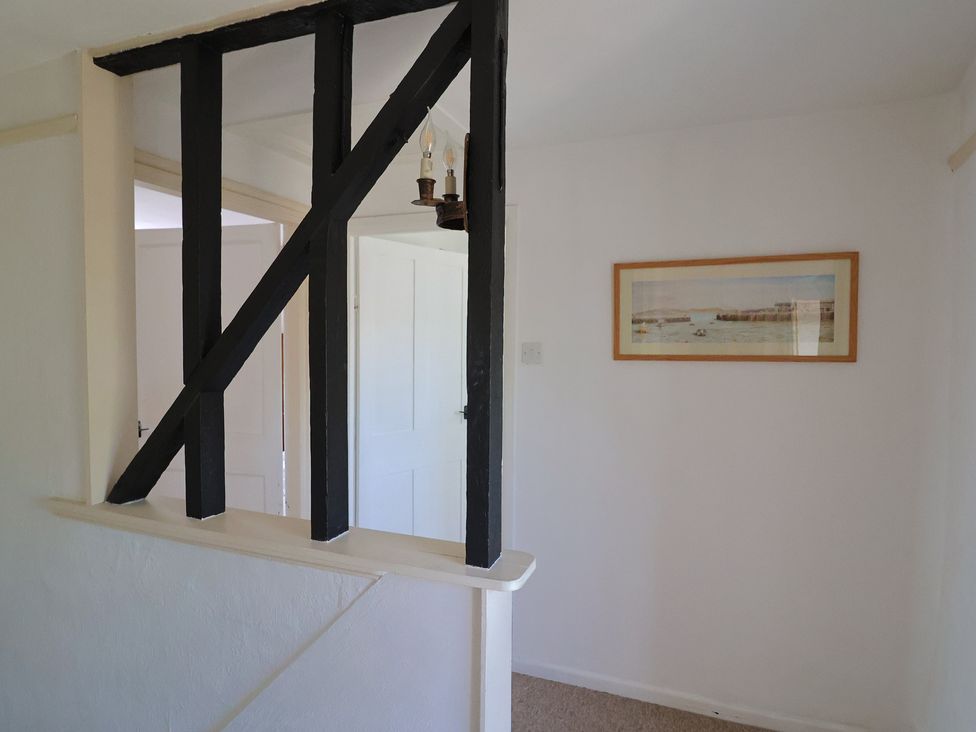 An interior space with white walls a framed picture on the wall black wooden beams and white doors at Milton Cottage in Lyme Regis