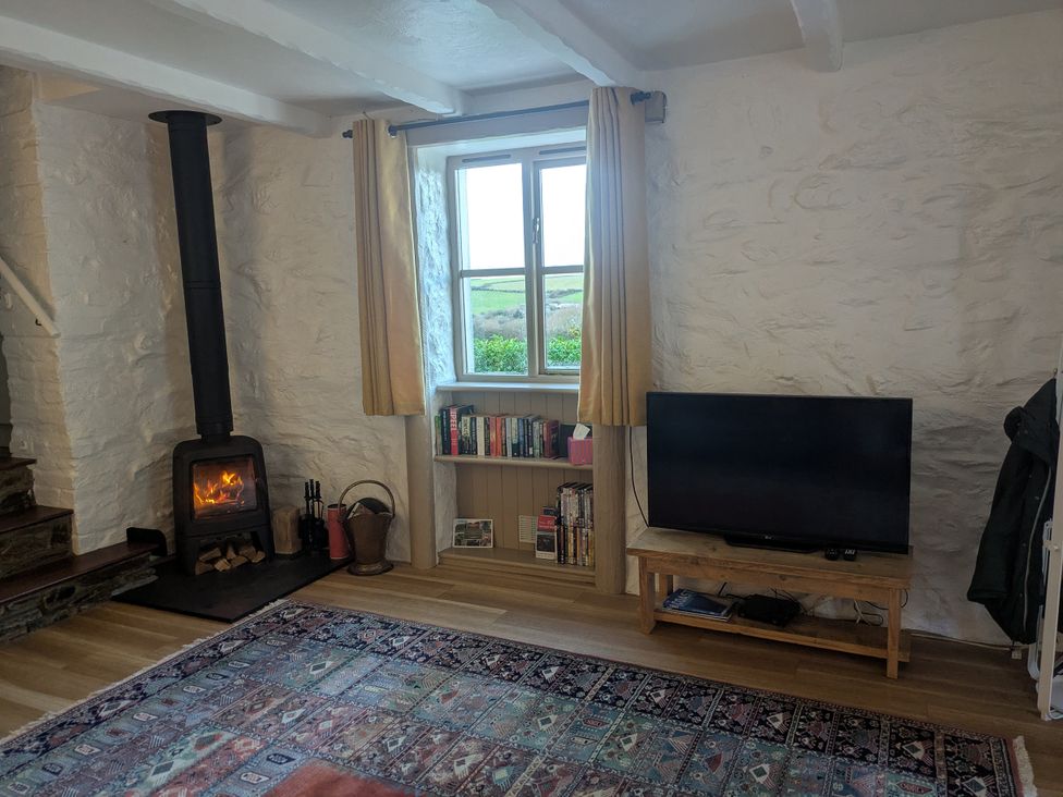 A living room with a fireplace and a tv at Babes Cottage in Perranwell near Goonhavern