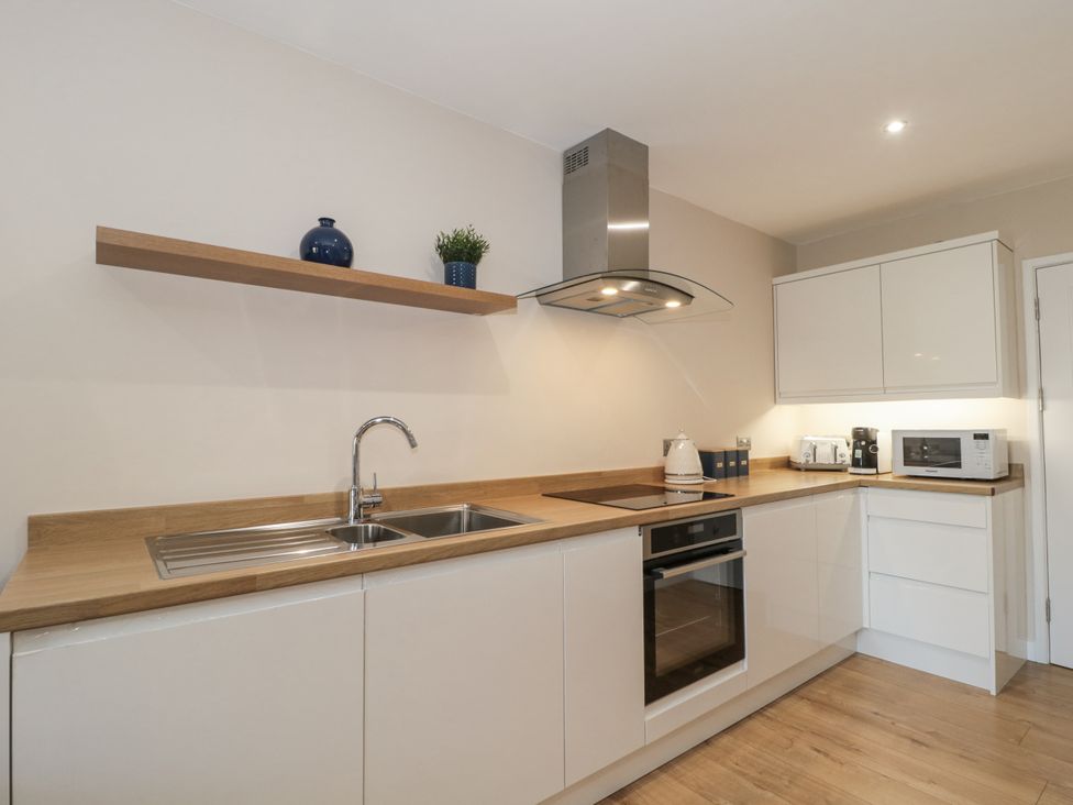 A kitchen with sink, cooktop, oven, and appliances at Royal Terrace Sunset in Weymouth