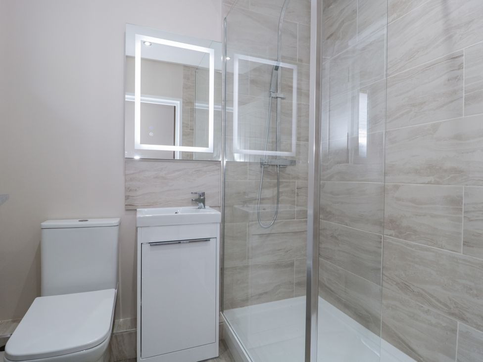 A bathroom with a toilet, sink, and shower at Royal Terrace Sunset in Weymouth