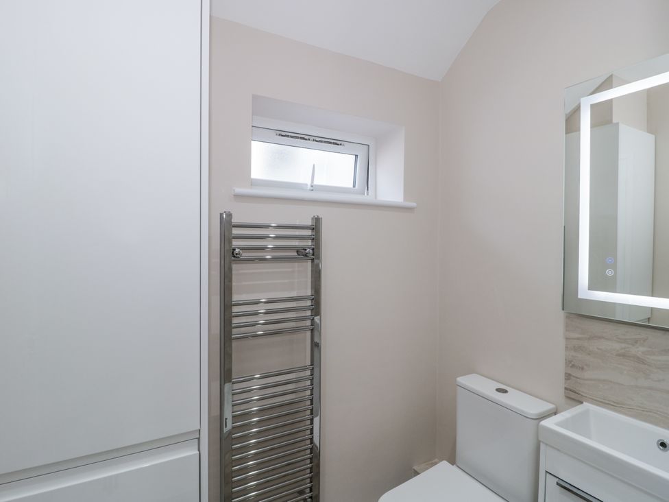 A bathroom with a toilet, sink, mirror, and towel rail at Royal Terrace Sunset in Weymouth