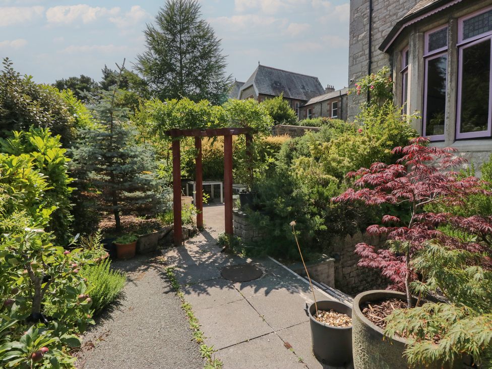 A garden with a pathway and archway at Lilac Cottage in Grange-Over-Sands