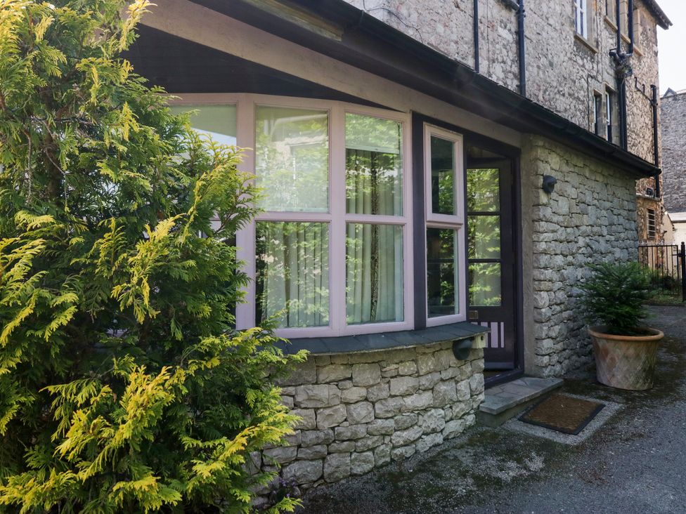 An exterior view of a house with stone wall and plants at Lilac Cottage in Grange-Over-Sands