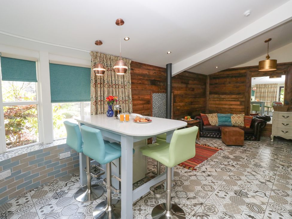 A kitchen with a bar stools and a table at Lilac Cottage in Grange-Over-Sands