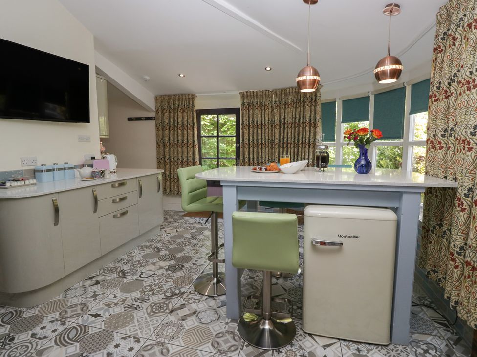 A kitchen with a table and stools at Lilac Cottage Grange-Over-Sands