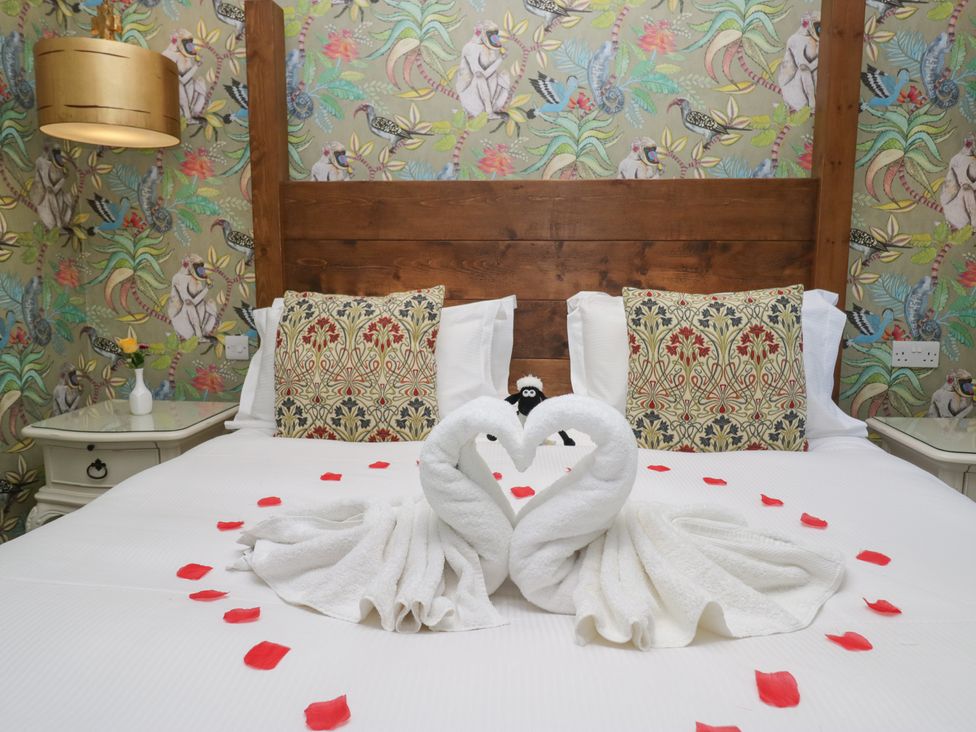 A bedroom with a bed and towel swans at Lilac Cottage in Grange-Over-Sands