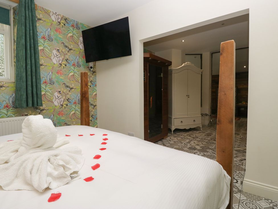 A bedroom with a bed, towels, and a television at Lilac Cottage in Grange-Over-Sands