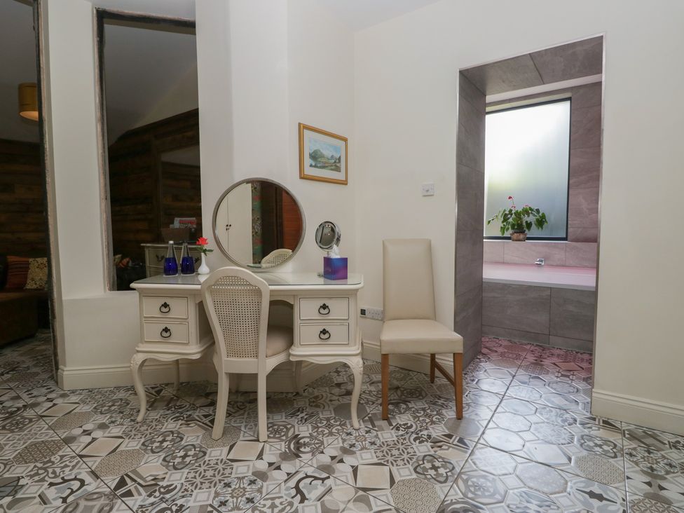 A vanity with a chair and a bathtub at Lilac Cottage in Grange-Over-Sands