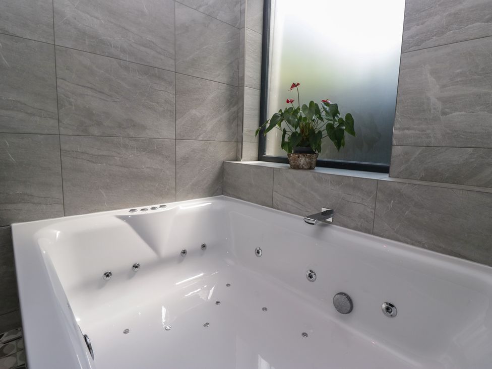 A bathroom with a bathtub and a plant at Lilac Cottage in Grange-Over-Sands