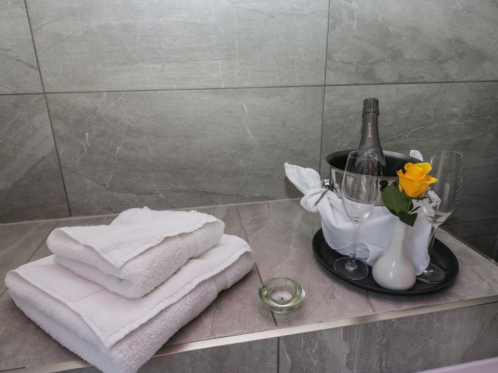A bathroom with towels and champagne on a tray at Lilac Cottage in Grange-Over-Sands