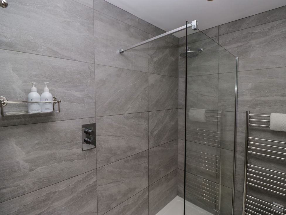 A shower area with a glass panel at Lilac Cottage in Grange-Over-Sands