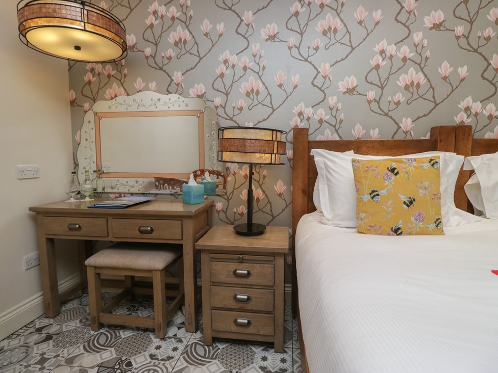 A bedroom with a bed, desk, and lamp at Lilac Cottage in Grange-Over-Sands