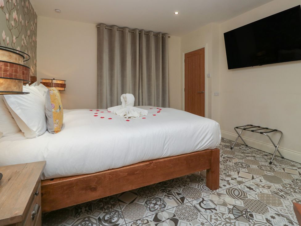 A bedroom with a bed and a television at Lilac Cottage in Grange-Over-Sands