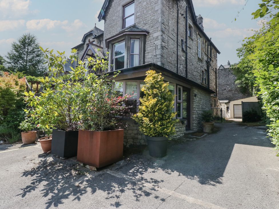 A stone building with trees and potted plants at Lilac Cottage in Grange-Over-Sands