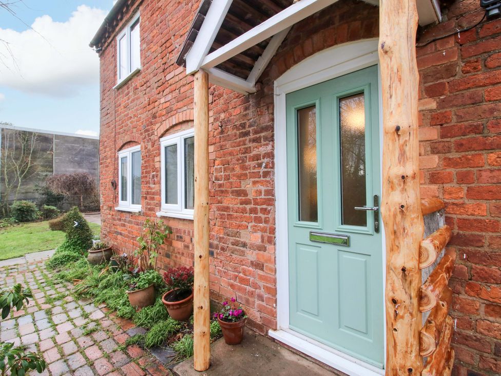 A front entryway with a brick wall and a green door at 1 Dingle Cottage in Worcester