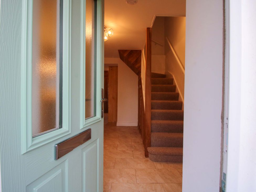 A hallway with a staircase and front door at 1 Dingle Cottage Worcester