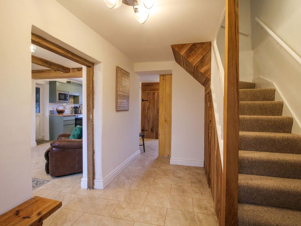 A hallway with a staircase and doorways at 1 Dingle Cottage in Worcester