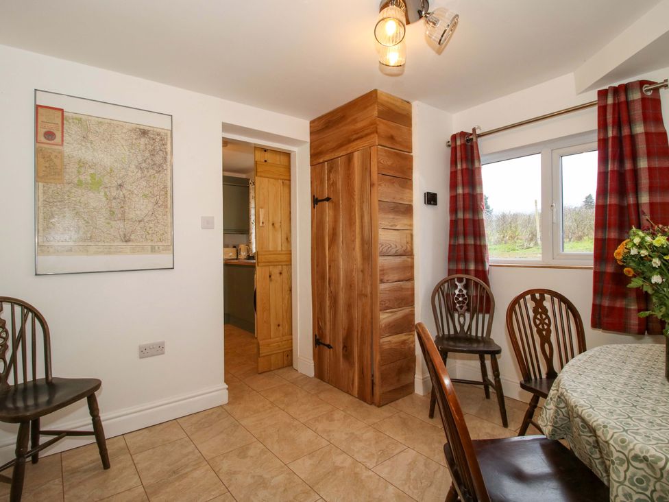 A dining room with a map on the wall and a wooden cabinet at 1 Dingle Cottage in Worcester