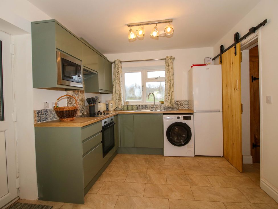 A kitchen with appliances and storage at 1 Dingle Cottage in Worcester