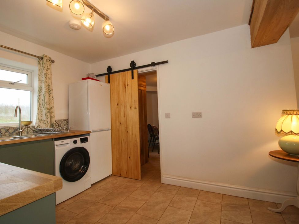 A kitchen with a fridge and washing machine at 1 Dingle Cottage in Worcester