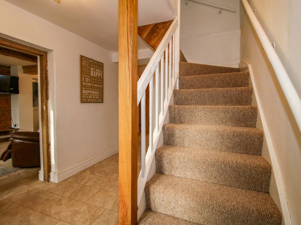 A staircase with carpet and a sign on the wall at 1 Dingle Cottage in Worcester