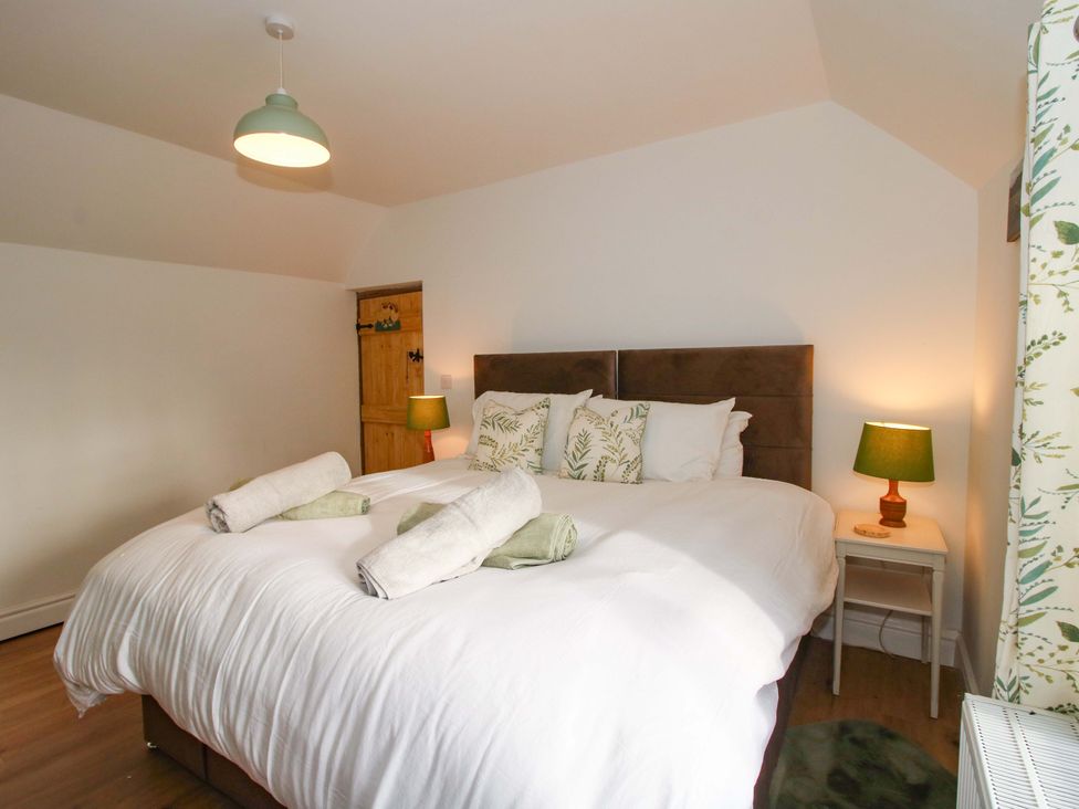 A bedroom with a bed and bedside table at 1 Dingle Cottage in Worcester