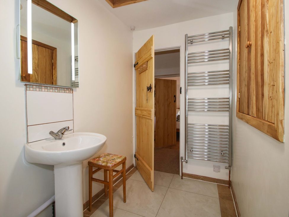 A bathroom with a wash basin and a mirror at 1 Dingle Cottage in Worcester