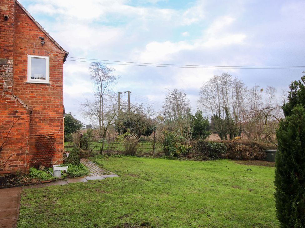 A garden with grass and trees at 1 Dingle Cottage in Worcester