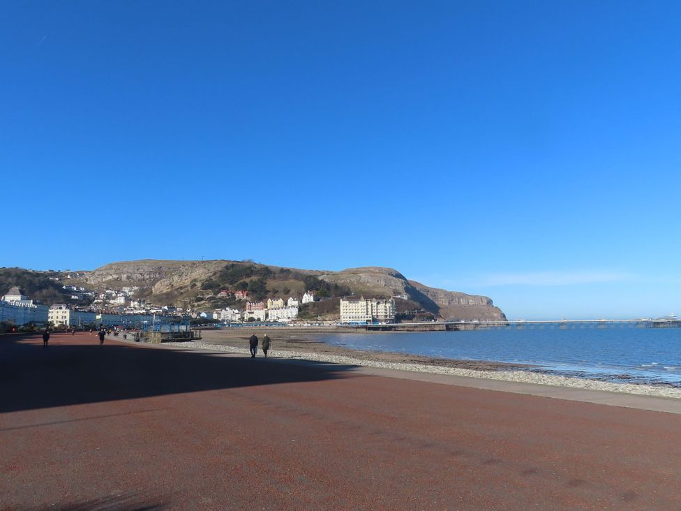 A waterfront view with people walking along the boardwalk at Fox House in Llandudno