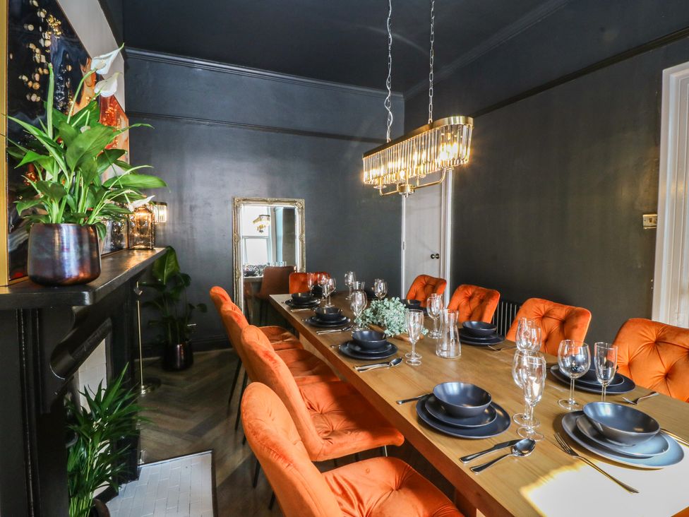A dining room with a long table set for a meal at Fox House in Llandudno