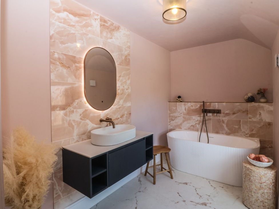A bathroom with bathtub and vanity unit at Fox House in Llandudno