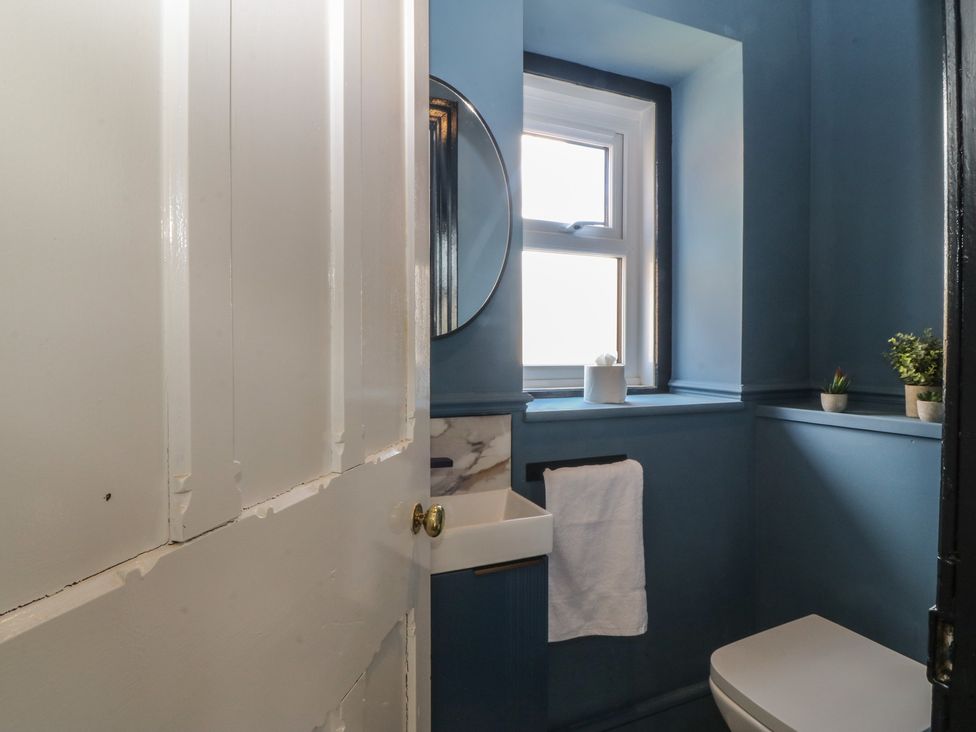 A bathroom with a sink, toilet, and window at Fox House in Llandudno