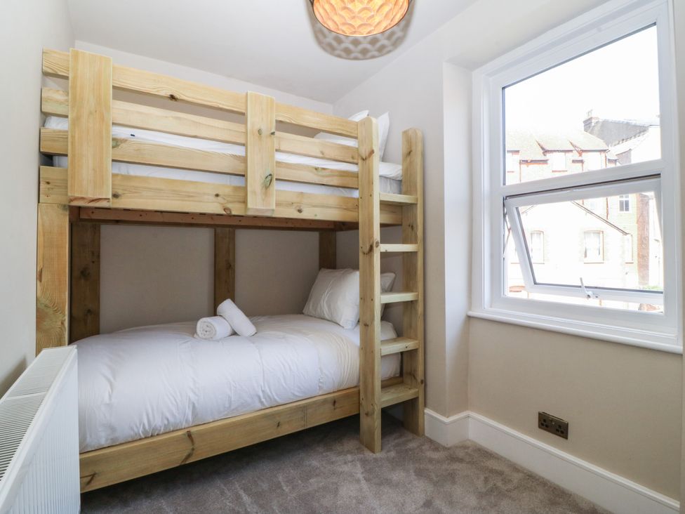 A bedroom with a bunk bed and window at Fox House in Llandudno