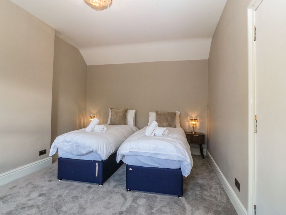 A bedroom with two single beds and bedside table at Fox House in Llandudno