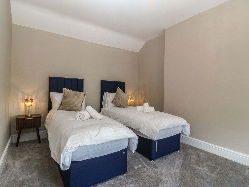 A bedroom with two single beds and a nightstand at Fox House in Llandudno