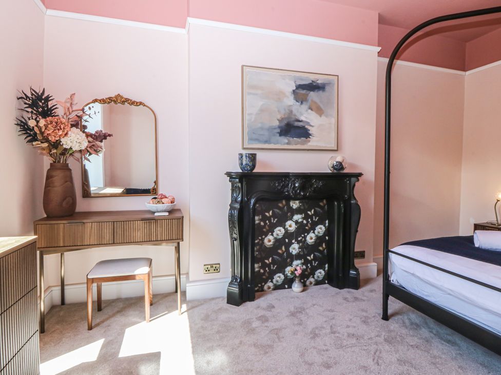 A bedroom with a bed and a fireplace at Fox House, Llandudno