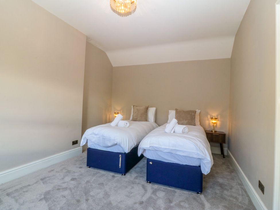 A bedroom with twin beds and bedside tables at Fox House in Llandudno