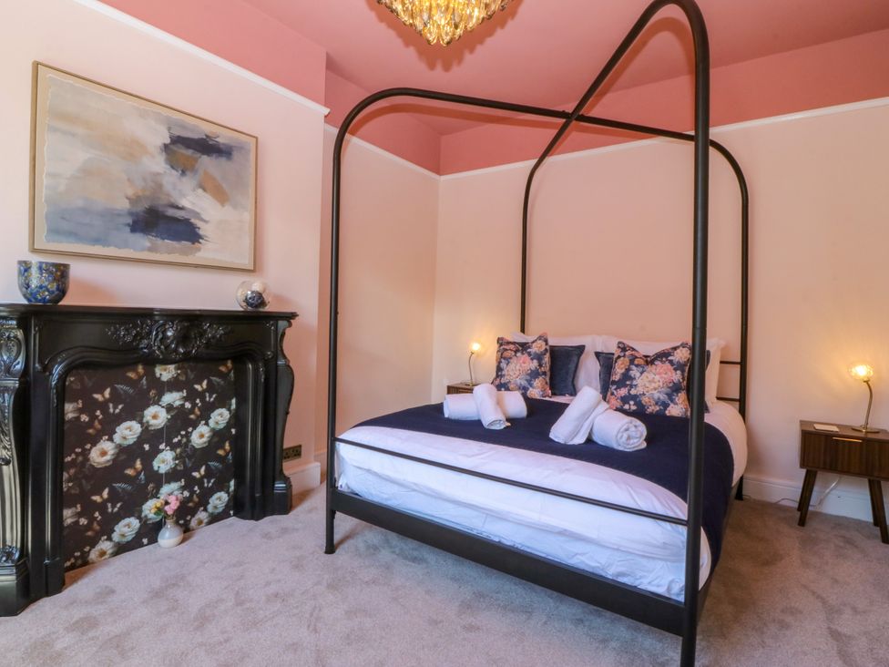 A bedroom with a four-poster bed and a fireplace at Fox House in Llandudno