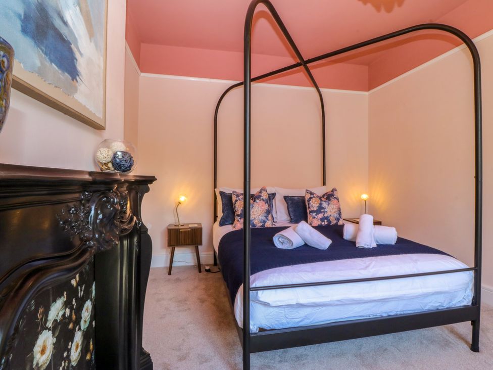 A bedroom with a four-poster bed and decorative pillows at Fox House in Llandudno