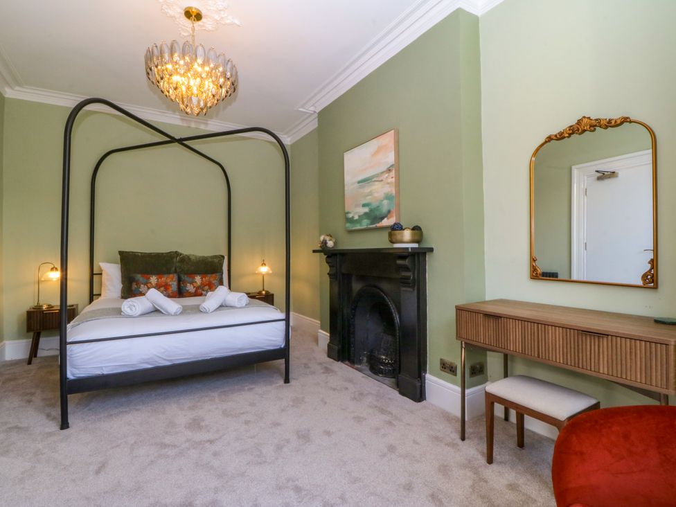 A bedroom with a four-poster bed and a fireplace at Fox House in Llandudno